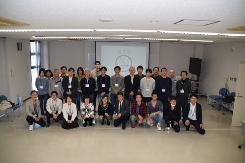 明るい室内でスクリーンの前に並んでいる人たちの集合写真