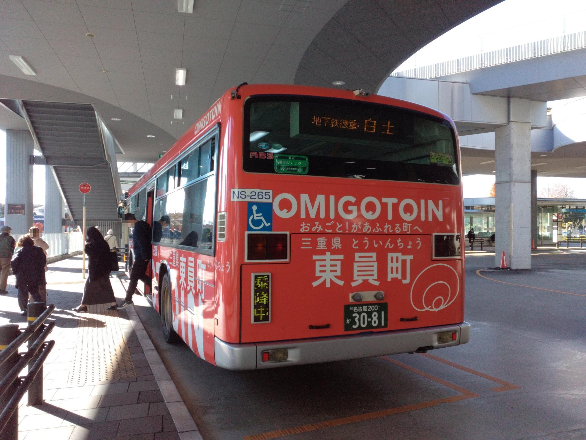 赤を基調としたデザインでOMIGOTO(おみごと)の文字をボディーへ印字した東員町をPRするラッピングバスの後方からの様子