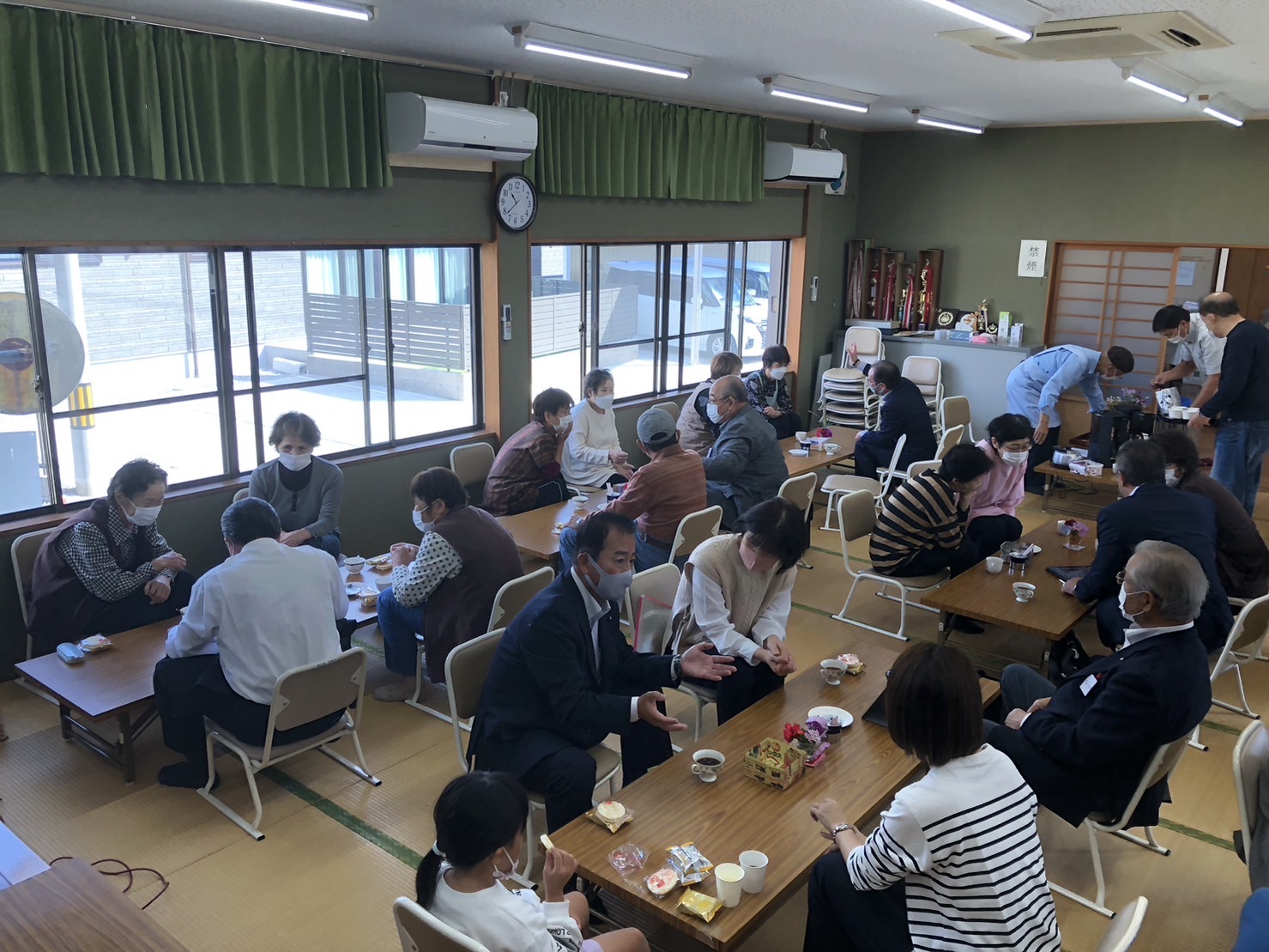 町民と議員たちがそれぞれテーブルにつき意見交換や報告をしている写真