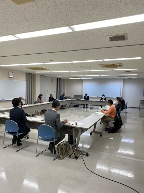 四角く並べられた机で向かい合いながら会議をしている様子の写真