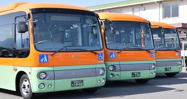 オレンジと薄緑色のバスが三台並んでいる写真