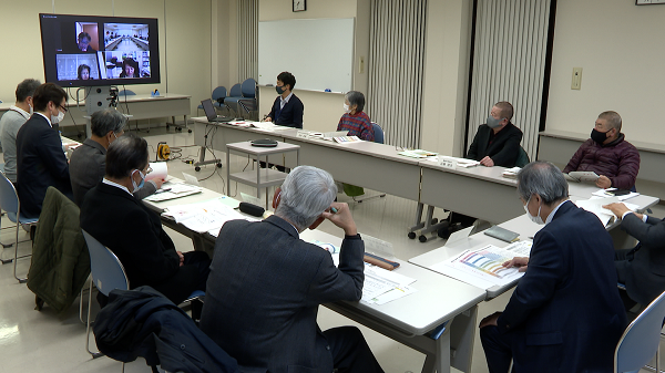 コの字型に並べられた机でオンライン会議をする人たちの写真