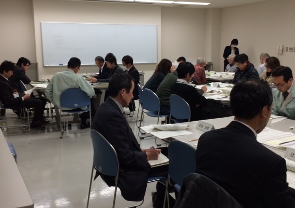 資料を読んだりメモを取ったりする人たちの写真