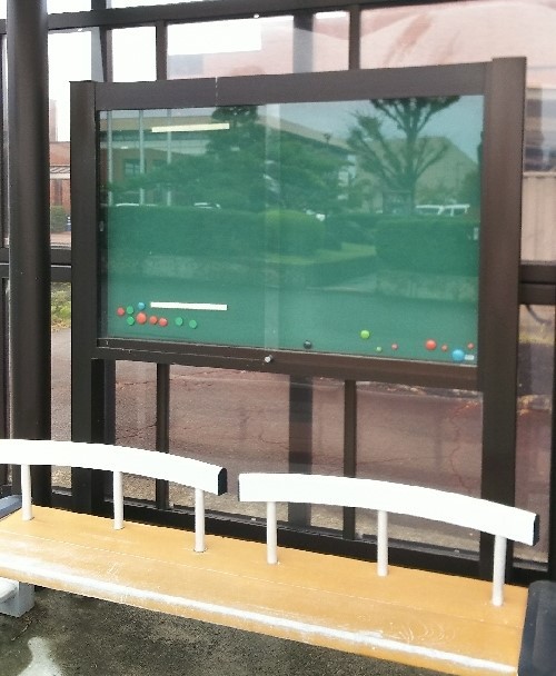 バス停留所にある緑色の広告掲載場所の写真