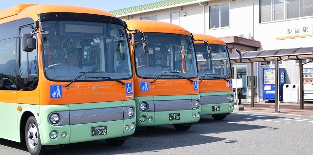 オレンジとグリーンの車体のバスが三台並んでいる写真