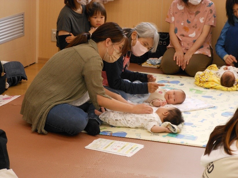赤ちゃんを寝かせて手遊びをする女性の写真