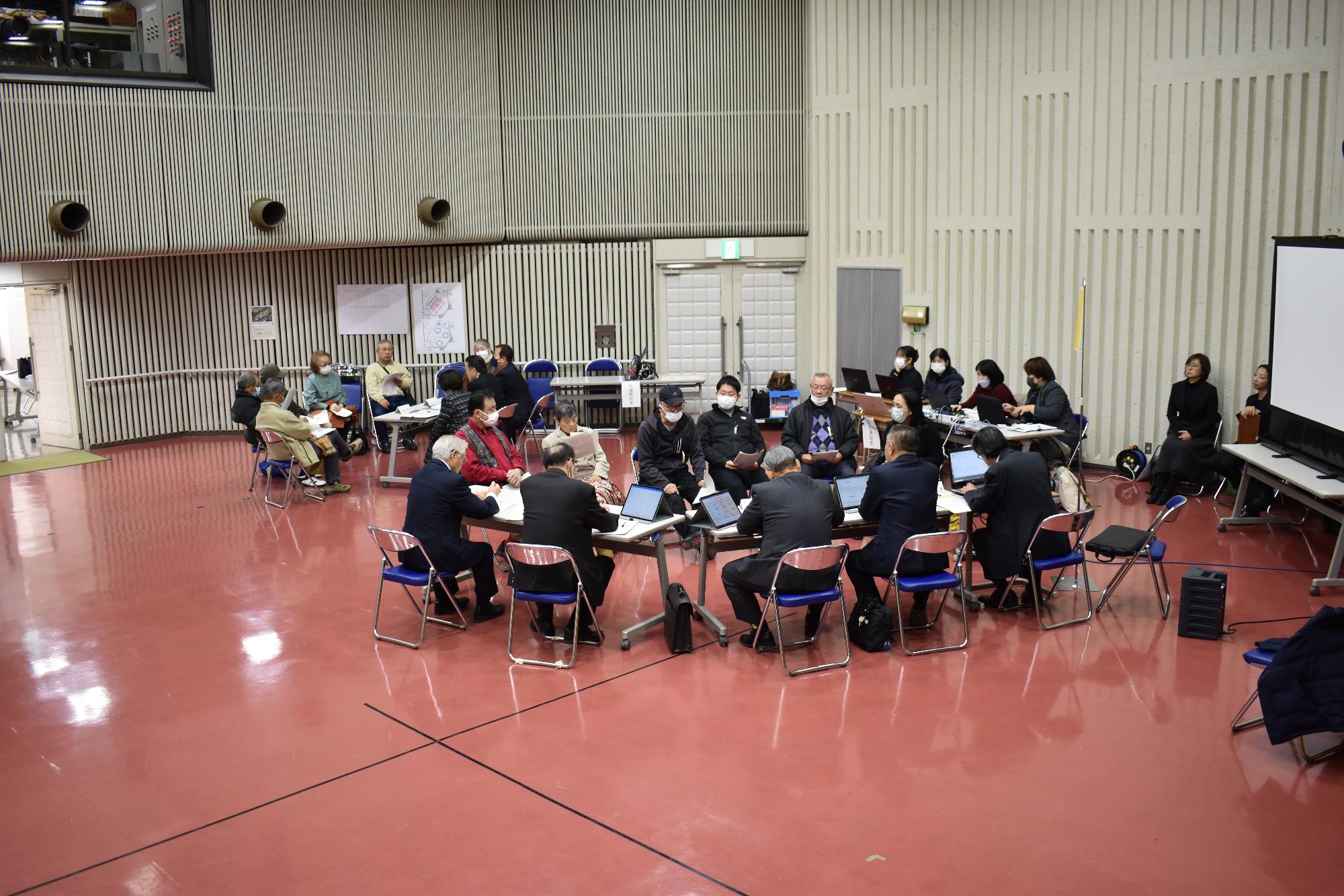 議会報告と意見交換を議員たちと町民たちがテーブルを囲んで行っている写真
